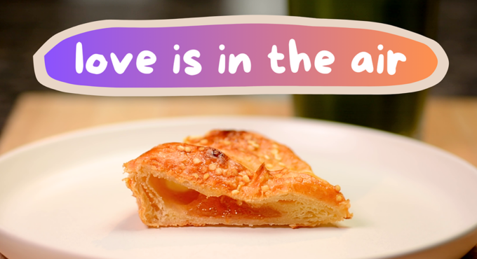 Photo of half an apricot croissant on a plate, with the text above it saying "love is in the air"